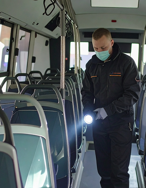 man inspecting a bus with mask and flashlight
