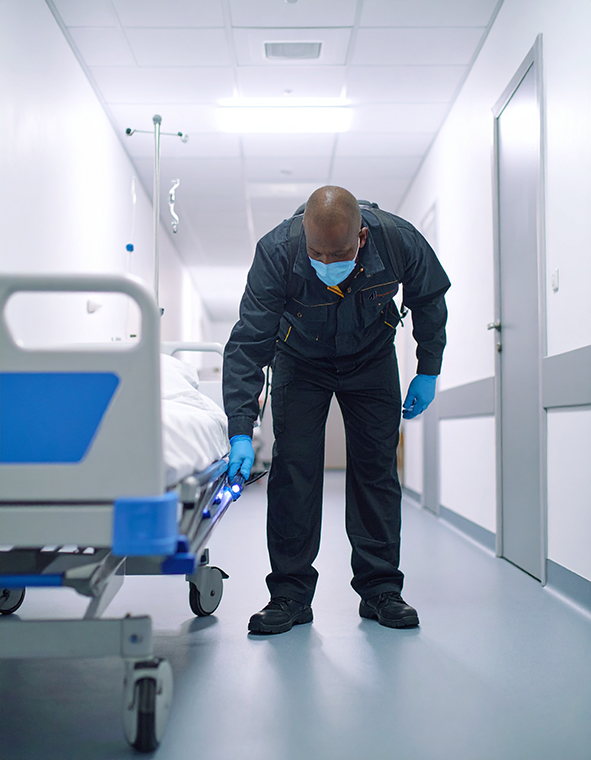 A male pest control technician inspecting a hospital bed