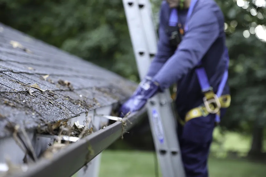 man on ladder cleaning gutter