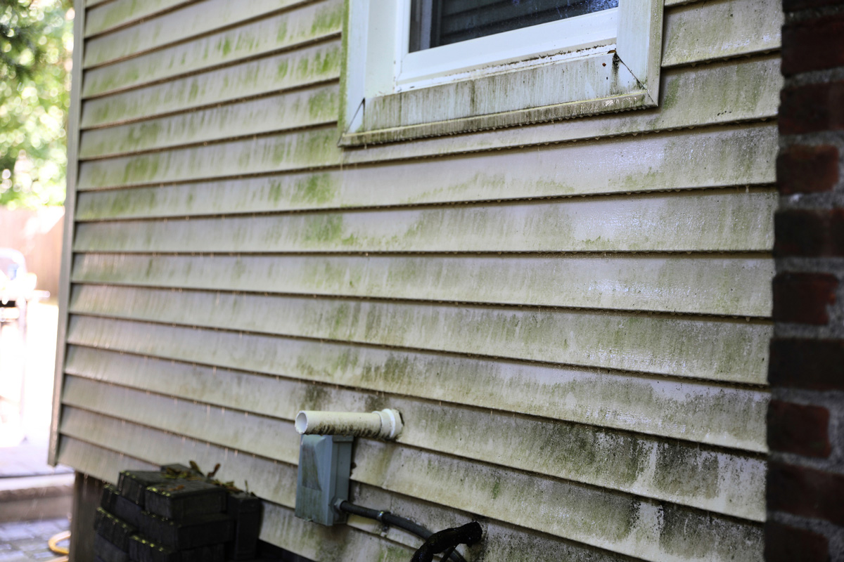 power-washing on a dirty house siding before